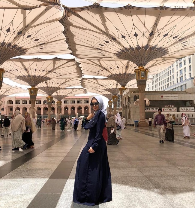 Inilah gaya Krisdayanti yang tengah jadi sorotan karena tampil glamour saat umrah. KD demikian dia biasa disapa sedang menjalani umrah Ramadan bersama suaminya, Raul Lemos. Berpose di halaman Masjid Nabawi, Madinah, KD terlihat memakai gamis panjang dengan hiasan mutiara, matching dengan kacamata hitamnya yang juga dihiasi bebatuan berkilau. Foto: Dok. Instagram