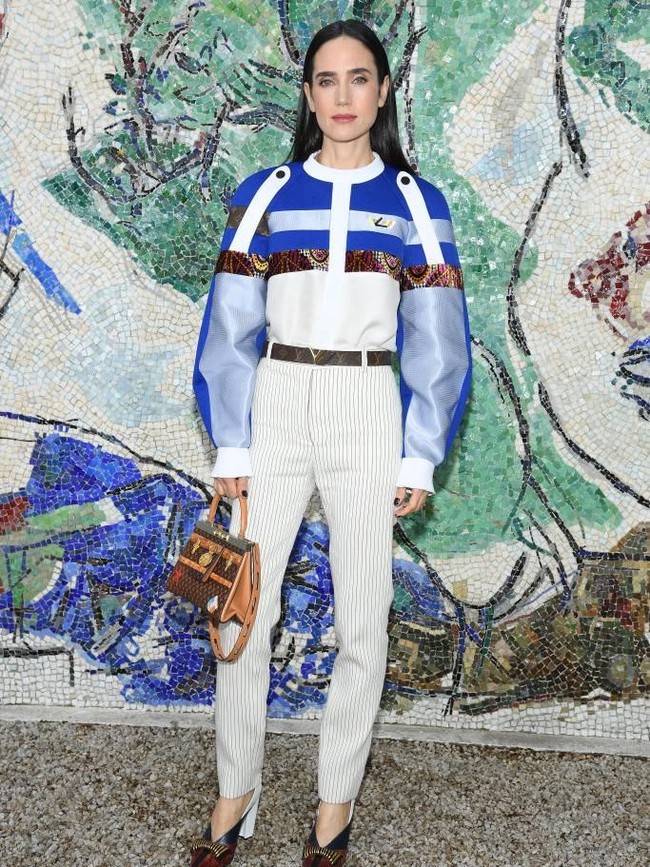 Aktris Jennifer Connelly tampil modis dengan atas bervolume yang eksentrik berikut, celana panjang putih high-waisted serta tas Louis Vuitton bergaya klasik. (Foto: Getty Images)