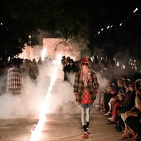 Para model berjalan di halaman Promenade Des Alyscamps ditemani obor dan lilin gereja. Suasana pun kian terasa mistis berkat perapian panjang yang membelah catwalk tersebut. (Foto: AFP PHOTO / BERTRAND LANGLOIS)