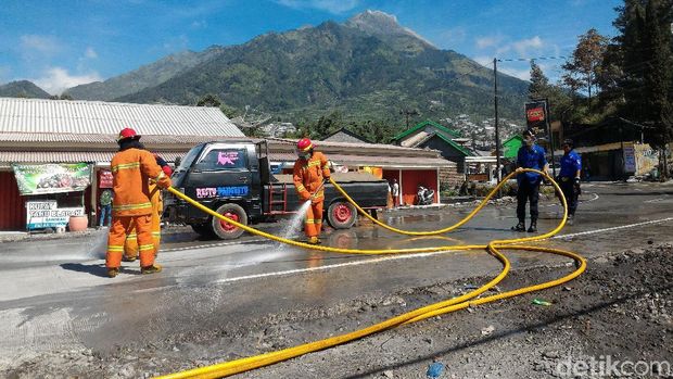 Tim pemadam kebakaran menyiram abu yang menyelimuti jalanan di Kecamatan Selo, Boyolali. 