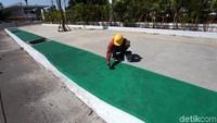Beberapa orang pekerja sedang mengecat jalur dipinggir pedestrian dikawasan Gelora Bung Karno (GBK) Senayan, Jakarta, Jumat (1/6).