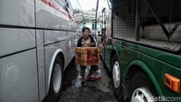 Seorang pemudik memasukkan kardus ke bagasi bus.