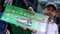 Pemudik menunjukkan tiket bus.