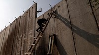 Seorang warga Palestina coba memanjang dinding pemisah untuk menghadiri salat Jumat di Tepi Barat (Foto: Dok. REUTERS/Ammar Awad)
