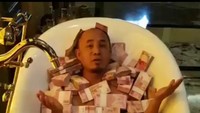 Pria yang belum diketahui identitasnya ini terlihat sedang mandi uang pecahan ratusan ribu. Dalam video yang viral, si pria mengaku bersyukur mendapat rezeki melimpah dan akan diinfaqkan. Foto: Screenshot Video Viral Mandi Uang (Dok Istimewa)
