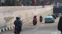 Tembok pagar underpass dicoret dengan cat semprot warna biru, merah, dan hitam. Kotorlah jadinya.
