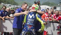 Sambil mengenakan helm barunya, Rossi merayakan keberhasilannya meraih pole bersama kru timnya. (Foto: Mirco Lazzari gp/Getty Images)
