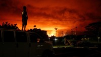 Warga menyaksikan letusan gunung dengan naik ke atap mobil. REUTERS/Terray Sylvester.