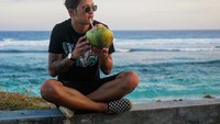 Pensiun jadi pemain timnas, kini Syamsir Alam punya profesi baru sebagai host program televisi My Trip My Adventure. Begini nih gayanya saat minum air kepala di pinggir pantai. Foto: Instagram @syamsir11alam