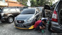 Pekerja melakukan perawatan mobil.