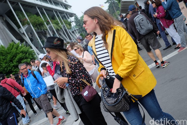 Udara sejuk di Roland Garros 2018 memungkinkan para fashionista pecinta tenis bereksperimen dengan outerwear. Wanita ini memasangkan jaket kuning bergaya jas hujannya dengan gaya kasual yang chic. Foto: Daniel Ngantung/Wolipop