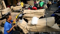 Pekerja tengah membungkus motor menggunakan kardus.
