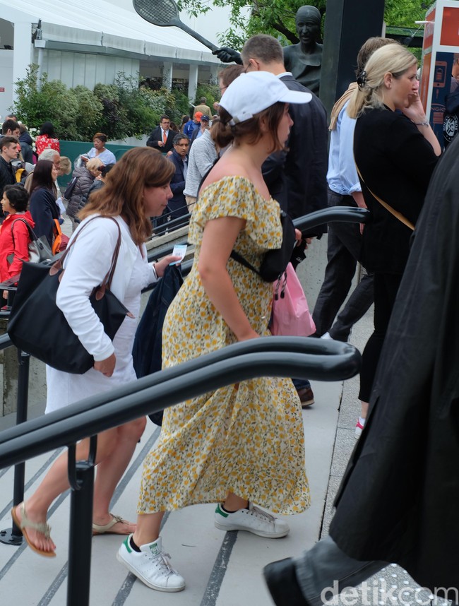 Pengunjung Roland Garros 2018 yang satu ini mencoba tampil beda dengan  off-shoulder dress bermotif bunga, yang dipasangkan dengan fanny-pack hitam, topi baseball putih, serta sneakers putih.  Foto: Daniel Ngantung/Wolipop