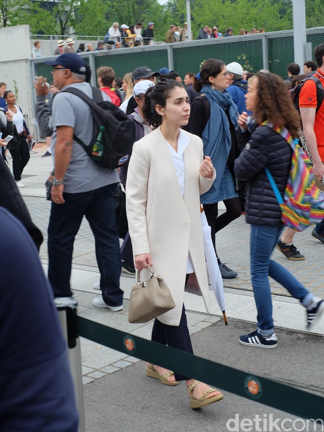 Coat berwarna beige dengan desain yang minimalis menjadi andalan penoton Roland Garros ini. Ia menyempurnakan gayanya dengan handbag dan wedges coklat, berikut payung putih yang senada dengan blusnya. Tres chic!  Foto: Daniel Ngantung/Wolipop
