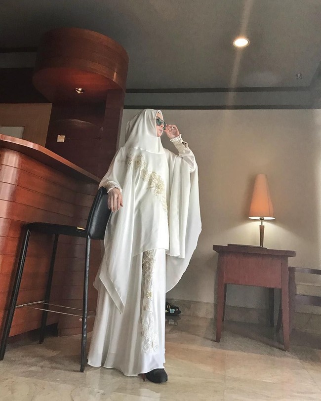 Cindy Fatika Sari juga memiliki label syari bernama Syaira Syari. Salah satu tampilan khimar set berwarna putih ini juga cocok dipakai saat salat Idul Fitri. Detail sulam yang simple di bagian bawah gamis mempercantik tampilanmu. Foto: Instagram/Sarahvi