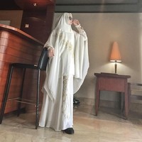Cindy Fatika Sari juga memiliki label syari bernama Syaira Syari. Salah satu tampilan khimar set berwarna putih ini juga cocok dipakai saat salat Idul Fitri. Detail sulam yang simple di bagian bawah gamis mempercantik tampilanmu. Foto: Instagram/Sarahvi