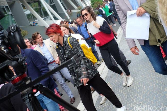 Sementara itu, penikmat tenis lainnya memilih jaket kamuflase transparan yang kontras dengan rambut merah dan tas kuningnya yang mencolok. Foto: Daniel Ngantung/Wolipop