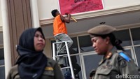 Petugas memasang spanduk segel pada sebuah bangunan.