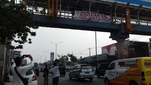Polisi saat mengecek spanduk yang dipasang di JPO Jalan Raya Serpong