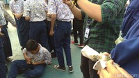 Begitu uang jatuh dari langit, murid-murid di lapangan mengangkat tangan tinggi-tinggi untuk meraih uang yang masih bertebaran di udara sebelum jatuh ke tanah.