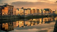 Perpaduan warna jingga dari matahari dan langit yang mulai kelabu ditambah refleksi bangunan-bangunan di sudut kota Dublin, Irlandia membuat momen matahari terbenam menjadi objek foto yang indah. Alex Baker/EyeEm via Getty Images.