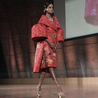 Sukses mencuri atensi, look pertama yang menampilkan gaun merah bersiluet coat dengan kerah dan lengan bervolume. Busana ini hadir dengan motif batik yang Denny tempel di atas bahan jacquard berkilauan dengan teknik bordir. Foto: Rio Motret/Image Dynamics