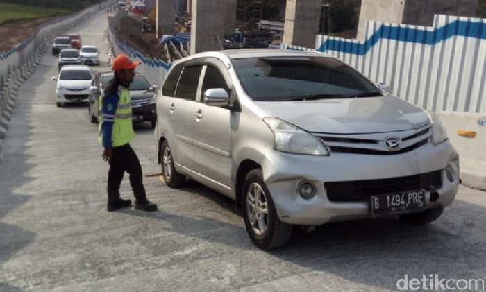 Petugas ganjal mobil yang tidak kuat di tanjakan Jembatan Kali Kenteng, Susukan, Kabupaten Semarang, Minggu (10/6/2018)