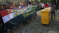 Massa melakukan aksi teatrikal dengan membawa sebuah tong sampah.