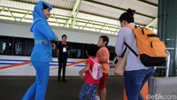 Seorang pramugari mengarahkan calon penumpang ke gerbong sesuai dengan nomor kursinya.
