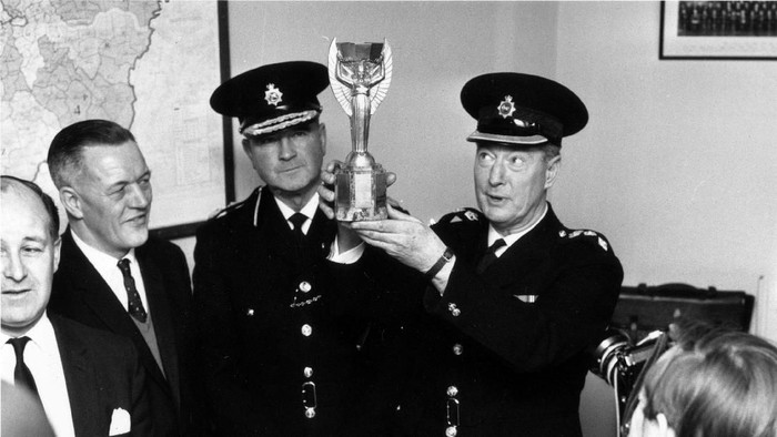 28th March 1966:  At Cannon Row police station, London, Chief Superintendent William Gilbert lifts the Jules Rimet trophy, (the  World Cup), for photographers.  With him are Detective Chief Inspector William Little, (left), and Commander John Lawler. The World Cup was stolen from the National Stamp Exhibition and found by Pickles, a dog out walking with his owner in Norwood, south London.  (Photo by Central Press/Getty Images)