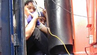 Potret pemudik yang duduk berdesak-desakan diantara penghubung gerbong kereta karena tidak mendapat tempat duduk.