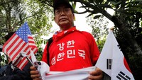 Pertemuan yang dilangsungkan di Singapura itu pun membawa masyarakat menyerukan perdamaian kepada pertemuan dua tokoh dunia itu. Tidak sedikit orang Korea datang ke Capella Hotel untuk menjadi saksi secara langsung pertemuan antara Kim Jong Un dan Donald Trump. Mereka terlihat membawa bendera Korea Selatan dan Amerika Serikat. Kim Kyung-hoon/Reuters.