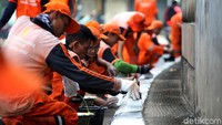 Sejumlah petugas PPSU tengah melakukan pengecatan trotoar.