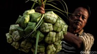 Seorang penjual ketupat di kawasan Pasar Warakas, Jakarta Utara, memamerkan dagangannya di depan kamera, Rabu (13/6/2018).