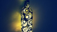 Botol bekas wine ini dilukis dengan bentuk lingkaran dan garis saja. Tapi saat bagian dalamnya diberi lampu maka jadilah lampu tidur yang keren. Tak perlu keluar uang untuk membeli lampu. Foto: Istimewa