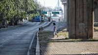 Seorang warga hendak menyebrang jalan dengan kondisi sepi dan lengang.