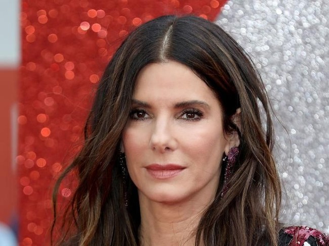 Sandra juga menyempurnakan gayanya dengan sepasang anting Lorraine Schwartz dan sandal-heels bergaya minimalis. (Foto: Tim P. Whitby/Getty Images)