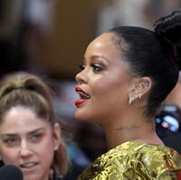 Untuk hair-do, Rihanna cukup tampil dengan gaya rambut cepol di atas. Tampak tiga deret anting cincin ikut menghiasi gayanya. (Foto: Tim P. Whitby/Getty Images)