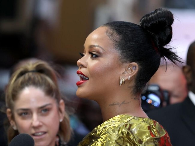 Untuk hair-do, Rihanna cukup tampil dengan gaya rambut cepol di atas. Tampak tiga deret anting cincin ikut menghiasi gayanya. (Foto: Tim P. Whitby/Getty Images)