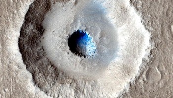  Sebuah kawah dingin ini tampak seperti bola mata dengan titik berawarna biru. Kawah bertingkat ini memperlihatkan berapa banyak es yang tersembunyi di bawah permukaan Mars. Gambar ini diambil pada tahun 2014 oleh Mars Reconnaissance Orbiter milik NASA. (Foto: NASA)