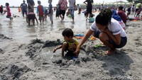 Warga yang membawa serta keluarganya masih memadati bibir pantai Ancol.
