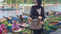 Sedang di pasar terapung Banjarmasin, Ratna tak melewatkan mampir membeli bahan makanan dan jajanan pasar. Gayanya tetep kece lho. Foto: Instagram @ratnagalih