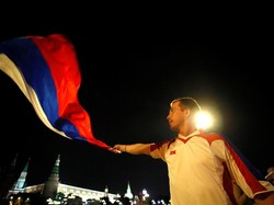 Seorang suporter mengibarkan bendera setelah tim nasional Rusia berhasil menundukkan Mesir. Maxim Shemetov/Reuters.
