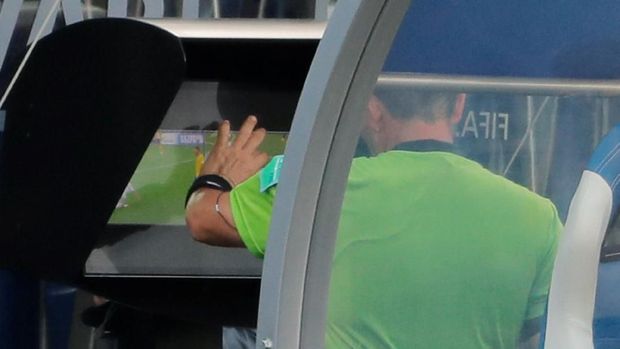 wasit meninjau sebuah insiden melalui tayangan ulang video di pinggir lapangan