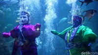 Sepasang ondel-ondel itu dipajang di dalam akuarium dan dikelilingi oleh ikan-ikan yang menghiasi akuarium tersebut.