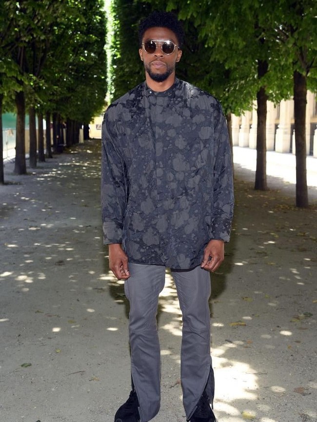 Chadwick Boseman, sang pemeran Black Panther, memilih busana serba abu-abu bermotif abstrak yang dipadu dengan celana jeans berwarna senada. Tampak sneakers hitam mengintip dari balik keliman jeans yang terbelah itu. (Foto: Getty Images)