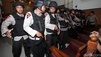 Belasan polisi bersenjata laras panjang membuat barikade memagari Aman Abdurrahman di ruang sidang.