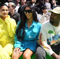 Kim duduk di samping Kylie Jenner yang memakai tracksuit kuning terang dan sepatu berbahan PVC. Hadir pula rapper Travis Scott, kekasih Kylie yang juga ayah dari putrinya, Stormi Webster. Foto: Dok. Getty Images