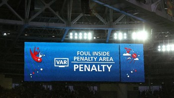 Layar rakasa di stadion memperlihatkan sistem VAR membantu wasit dalam mengambil keputusan penalti diberikan. Foto: Getty Images