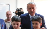 Erdogan ditemani cucunya saat memasukkan kertas suara ke kotak suara di TPS